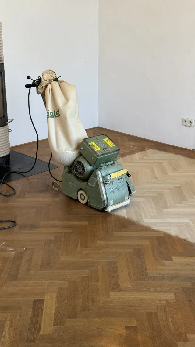 Handwerker bei einer Bodenarbeit mit einer Parkettschleifmaschine.