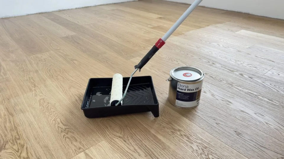 Reinigungsgerät und Pflegemittel auf einem Holzboden.